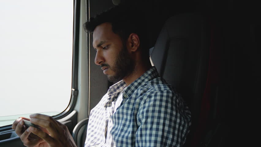 Professional indian trucker using truck gps navigation to transport and deliver goods to the destination. Right hand drive car