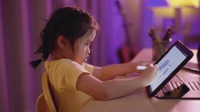 Asian girl smiling, laughing, excited, looking, wearing white headphone and using  pen touch on white screen tablet screen streaming night light. Cute girl watching videos while tv Internet addiction.