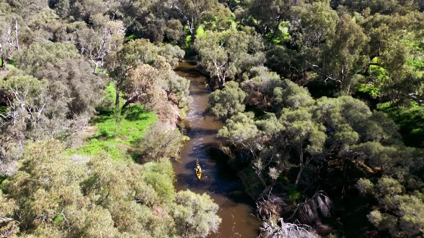Two man yellow Kayak travelling down stream in narrow river. Aerial tracking