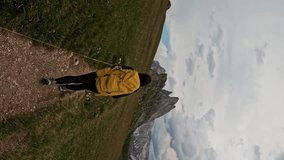 Vertical screen shot of woman with backpack hiking trail path and climbing Seceda Dolomites mountain. Summer adventure journey in nature outdoors. Travel exploring Alps, Dolomites, Italy