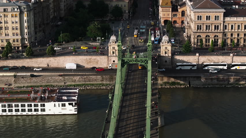Aerial footage of beautiful Szabadsag hid bridge over river Danube and buildings of waterfront lit by sunrays. Budapest, Hungary