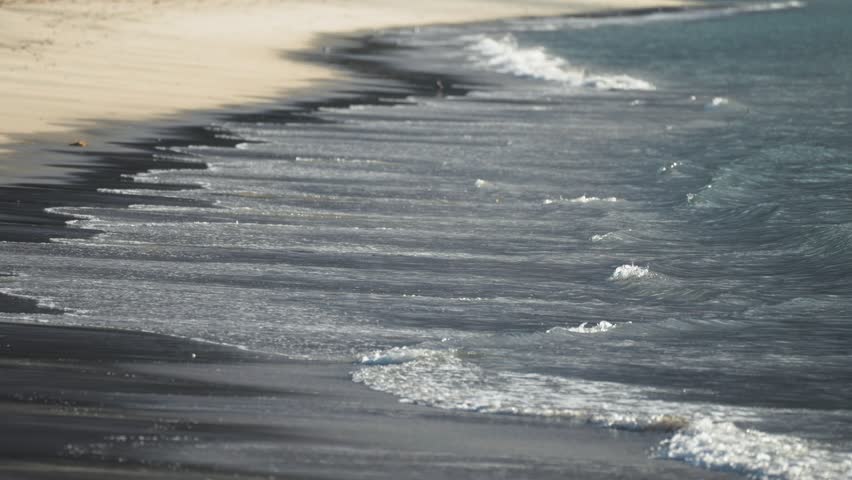 Waves gently roll onto the sandy beach. Parallax video.
