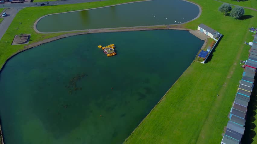 Revealing Drone View of Dovercourt Boating Lake with Colorful Beach Huts in the Background