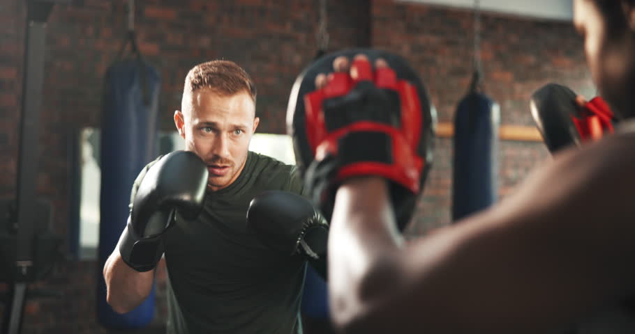 Sports coach, fitness man and boxer punch training, learning fighting skill or battle exercise, practice or muay thai workout. Gym club, partner teamwork or personal trainer coaching kickboxing power Royalty-Free Stock Footage #1108062691