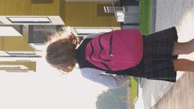 Vertical video. Schoolgirl with backpack running to classes in the morning, slow motion. Back to school