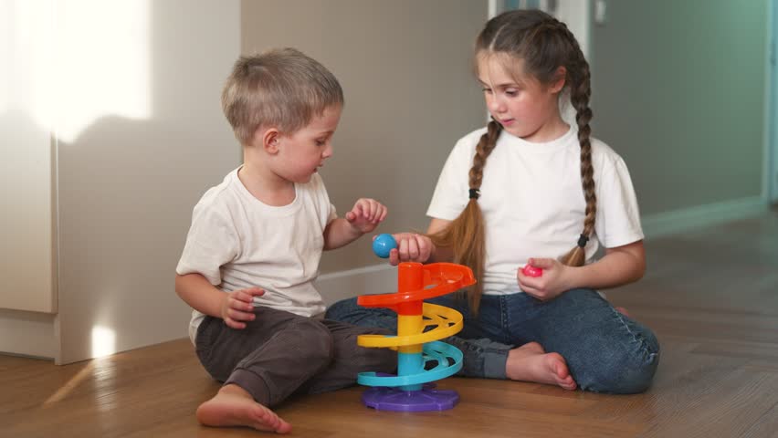 Children play floor room. Girl and boy play toys at home in the nursery. Children play with toys on the floor of the children's room. Two children play educational games for girl and boy Royalty-Free Stock Footage #1108068617