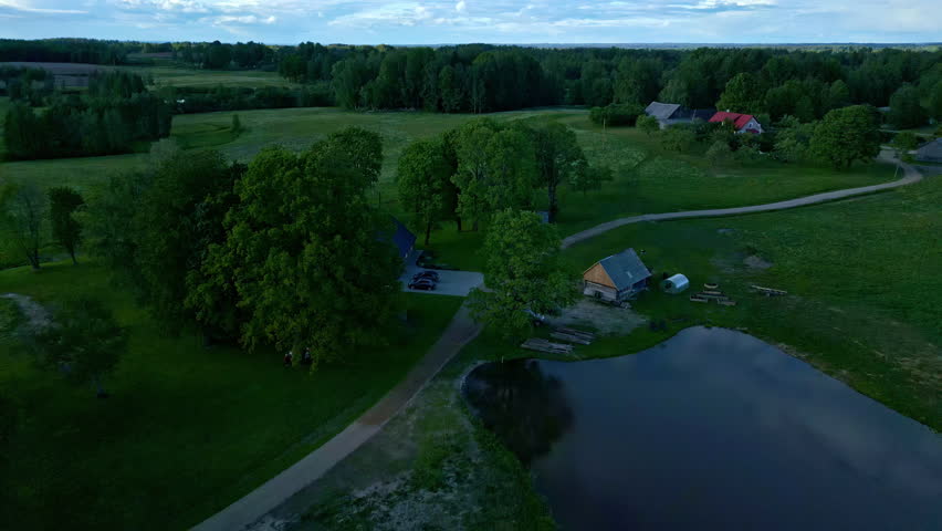 Aerial Perspective of a Wooden House Nestled Amidst Grass Fields and Woodlands.