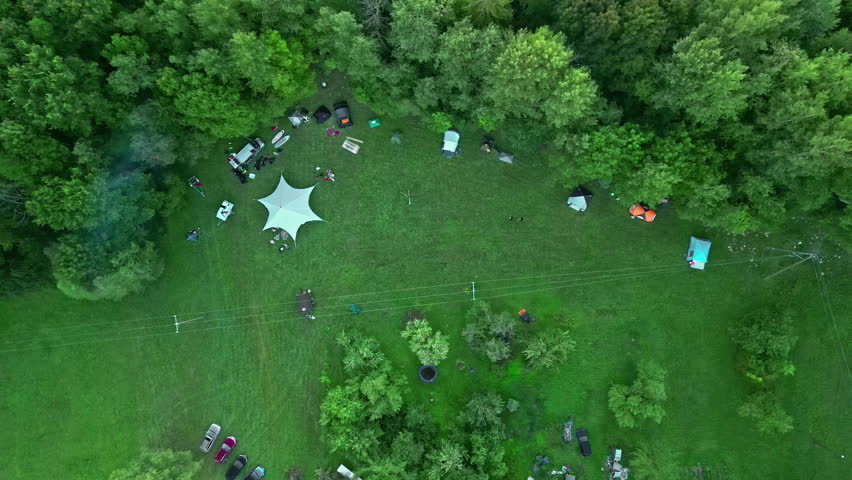 Campers gather in a forest meadow for outdoor leisure - straight down aerial view