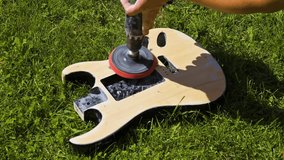 Man sanding electric guitar wood body with electric rotation instrument. 4k video footage UHD 3840x2160