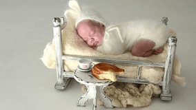 Sleeping newborn cute baby girl or boy during first week of life. 4k slow motion raw video. Breakfast concept. Small baby sleep in white vintage bed in white rabbit costume with breakfast on table