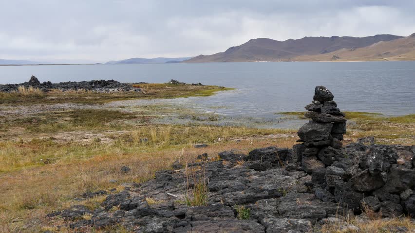 Man-made stone pillars made of volcanic stones on the shore of Tsagan Nuur Lake in autumn cloudy evening, Mongolia. | Shutterstock HD Video #1108070767