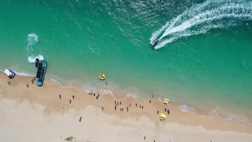 Top down view of outdoor enthusiasts enjoying jet skiing, banana boat riding and other water sports at a beautifu beach on Jibei Island, which is a popular summer holiday destination in Penghu, Taiwan