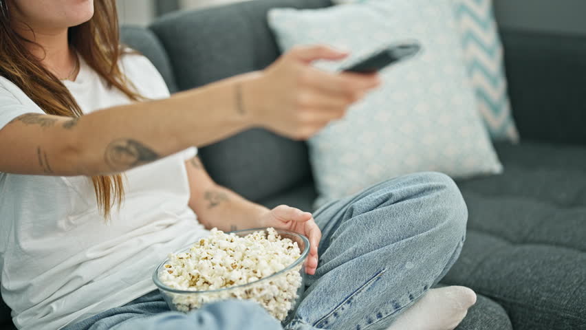 Young beautiful hispanic woman watching movie eating popcorn sitting on sofa at home Royalty-Free Stock Footage #1108073583