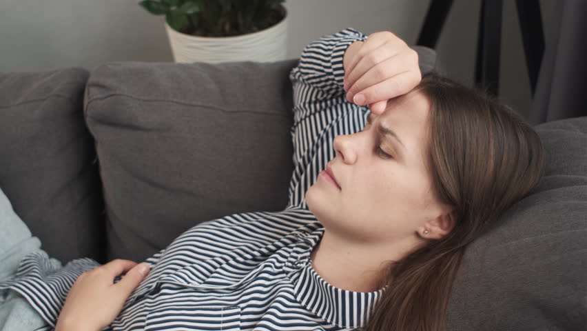 Depressed young woman lying on couch at home feeling headache fatigue loneliness. Close up of upset tired sick ill girl suffer from migraine anxiety, drowsy somnolent female rest on sofa after stress | Shutterstock HD Video #1108080349