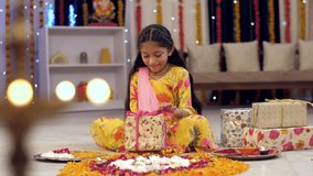 A cute little kid opening her Diwali gift box with a toothy smile on her face in India, festival time, decorated home. A closeup shot of a young girl opening a colorful birthday present with a happy - Powered by Shutterstock - Get 15% off with code: PIKWIZARD15