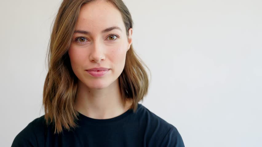 Smiling young female or woman looking in camera feeling happy and cheerful. Naturally girl in black t-shirt isolated on white background. Close-up	