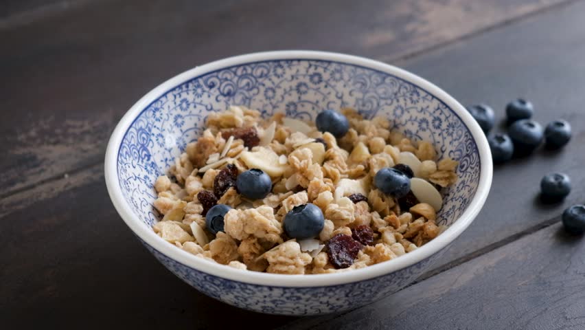 Slow motion of milk pouring in crunchy granola bowl served with fresh blueberries. Healthy breakfast meal | Shutterstock HD Video #1108092655