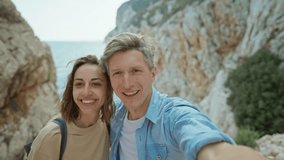 happy lovely couple young smiling woman and mid aged man hiking rocky canyon at seaside and taking selfie. wanderlust and travel summer vacation trip. using phone camera for filming - Powered by Shutterstock - Get 15% off with code: PIKWIZARD15