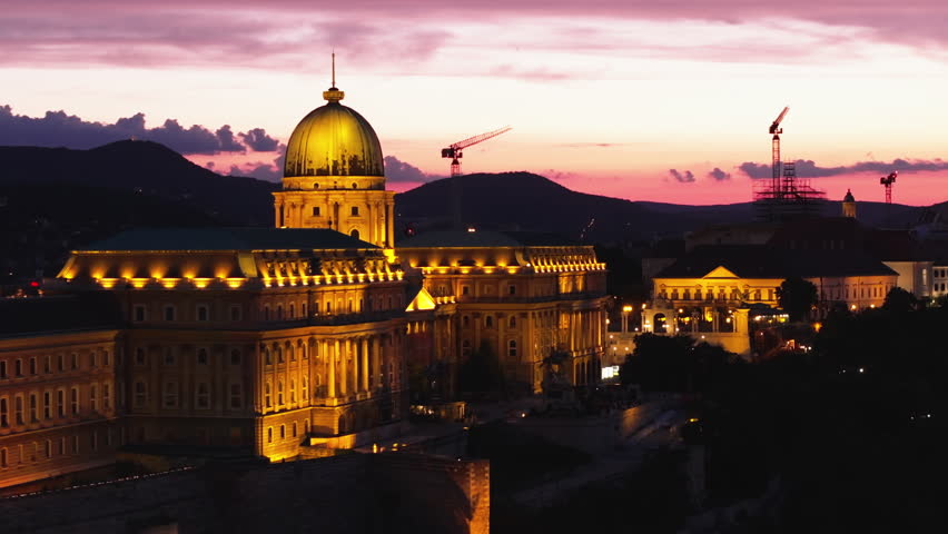 Aerial slide and pan footage of Buda Castle complex with large dome against colour twilight sky. Famous sights in evening. Budapest, Hungary