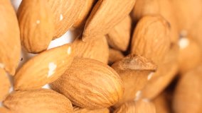 Macro video of freshly picked almonds slowly falling into a bowl. Brown nuts with a thin skin.