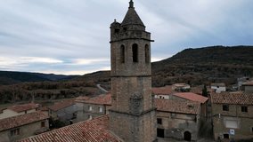 Panoramic drone view of old medieval traditional ancient architecture village houses of Luzas and church belltower of Romanesque church of San Cristobal. Province of Huesca, Aragon, Spain. 4K video