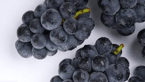 Slowly Moving Camera Captures 4K Video of Large Grapes Wet with Water on a White Background.
