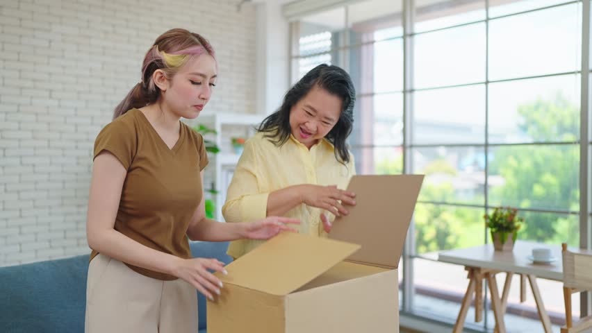 Young Asian woman with mature mother enjoy unpacking parcel together. Happy elderly mom and daughter excited unpacking cardboard box receiving ordered from internet store. Online Shopping | Shutterstock HD Video #1108114371