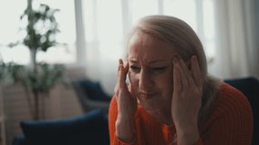Blond woman in her 50s suffering from migraine, massaging temples on sofa - Powered by Shutterstock - Get 15% off with code: PIKWIZARD15