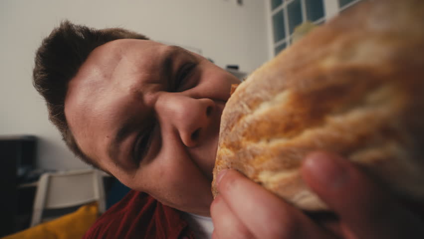 Funny overweight man biting a sandwich, feeling hungry, food addict, health risk