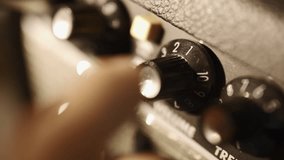Guitarist turning volume knob on guitar amplifier to 10 - Powered by Shutterstock - Get 15% off with code: PIKWIZARD15