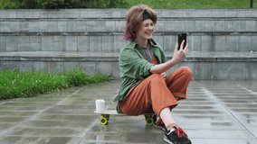 Gen Z beautiful young woman skater blogger video chatting using smartphone outdoors.