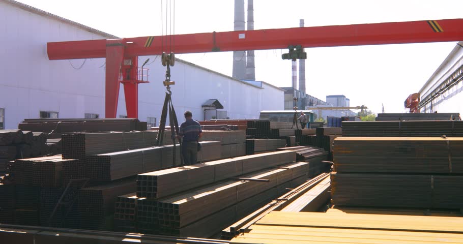 Worker preparing stack of metal pipes with gantry crane for transportation in the steel factory