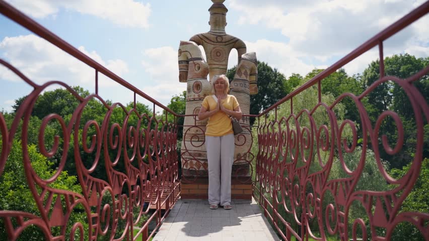 Mature woman meditation near a ceramic slavic statue, pagan culture. Active lifestyle, spirituality and mental healthy concept. 