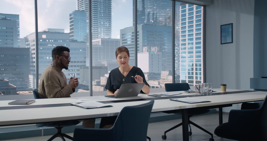 Businesspeople in Skyscraper Office: Business Meeting of Two Managers Using Laptop. Female CEO and African American Operations Director Discuss Strategy, Implementing Financial Plans. Royalty-Free Stock Footage #1108128787