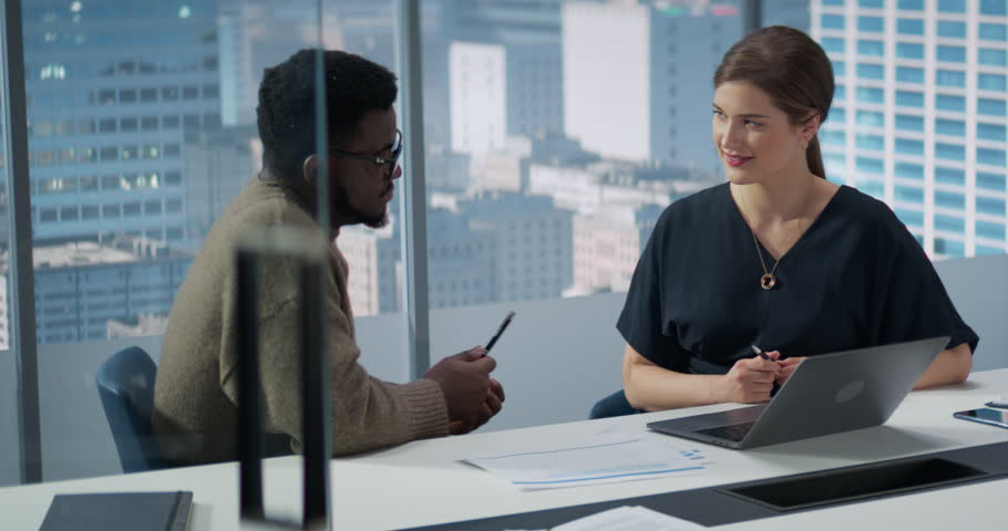 Businesspeople in Skyscraper Office: Business Meeting of Two Managers Using Laptop. Female CEO and African American Operations Director Succesfully Complete a Task And Fist Bump.