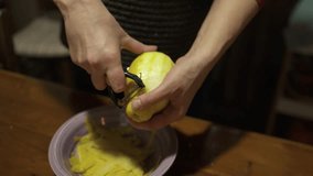 Homemade alcoholic drink limoncello in the home kitchen in the Italian village. Woman peeling lemon skin using a peeler 4K