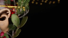 Vertical video. Small Christmas decorations, berries, and cinnamon sticks are placed on Santa's red hat for added fragrance. A sprig of fir is also added. The garland lights up against a black background - Powered by Shutterstock - Get 15% off with code: PIKWIZARD15