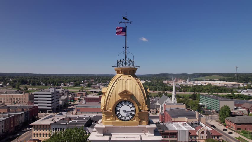 Aerial view and drone shot of clocktower government tower and building structure in the center of Newark, Ohio east of Columbus, OH with downtown buildings, small businesses, and residential district.