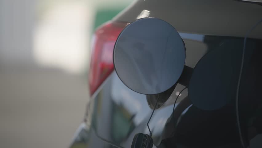 Slow motion of man and his hands filling his automobile car tank with unleaded gas and petroleum fuel at small gas station in close up on grey vehicle Royalty-Free Stock Footage #1108137499