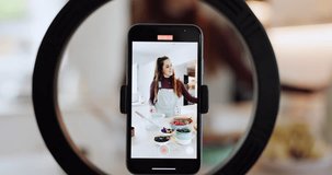 Influencer woman, cooking and live stream in kitchen, ring light or phone screen for web tutorial in house. Girl, chef and smartphone for recording, video or food for post on social media app in home