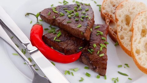 fresh hot grilled beef meat steak served with red hot pepper and white bun slices on plate over wooden table 1920x1080 intro motion slow hidef hd