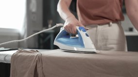 one young woman teenage student ironing clothes at home foo the first time hold iron on shirt on board household chores concept female living in the apartment alone doing housework slow motion - Powered by Shutterstock - Get 15% off with code: PIKWIZARD15