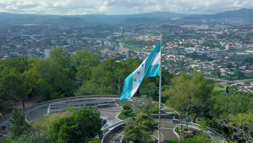 Aerial descending footage on the Honduran national flag, and with downtown Tegucigalpa as background Royalty-Free Stock Footage #1108141495