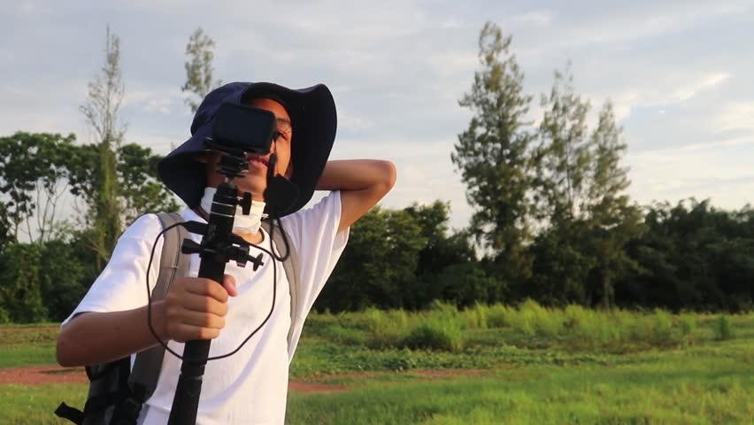 Asian boy holding an action cam introducing a tent on the lawn