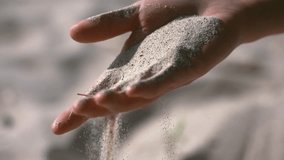 Slow motion video recording of a human hand with sand falling from it