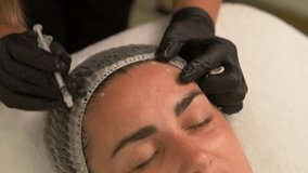 Beauty clinic. Beautician hands in gloves making face aging injection in a female skin. A woman gets beauty facial cosmetology procedure. . collagen injections. Shot in 4k