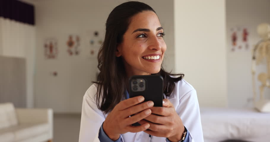 Close up happy Latina doctor use smartphone at workplace, messaging during break, share sms, lead personal chat, enjoy new medical mobile application for easy, comfortable communication with patients