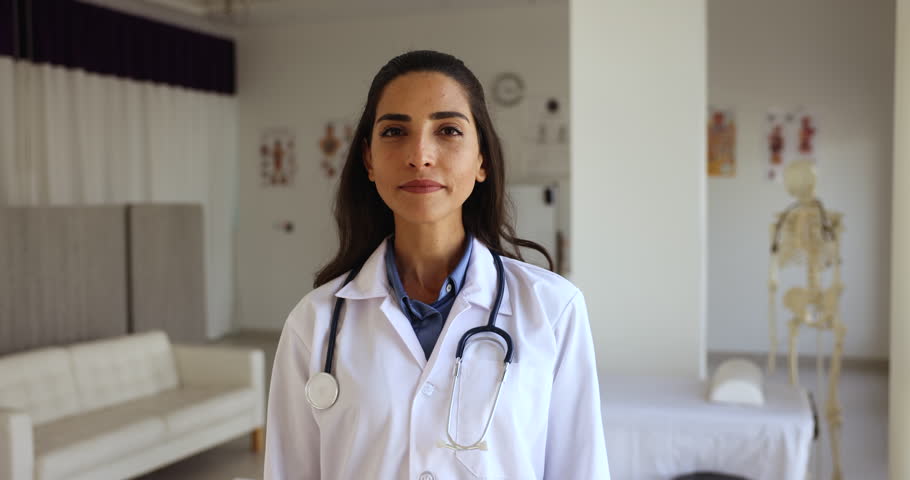 Happy Latina female general practitioner in white coat pose standing at workplace with arms crossed feels confident looks satisfied with career in private clinic. Professional medical worker portrait Royalty-Free Stock Footage #1108158207
