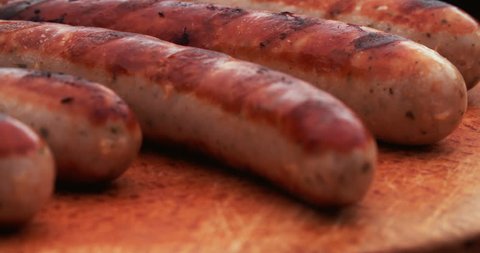 Freshly grilled bratwurst sausages presented on a vintage wooden board for an outdoor meal – Video có sẵn