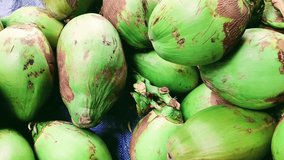 tender green coconut is kept for sale on a market with seller offering coconut water drinks for money.4k video